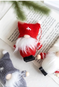 Detail of red knitted Christmas gnome ornament with white snowflake embroidery and beard