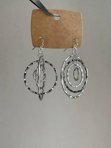 Close-up of layered silver hollow round earrings with textured metal loops on hooks