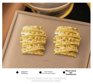 Detailed macro of 18k gold plated hammered earrings with irregular textured surface