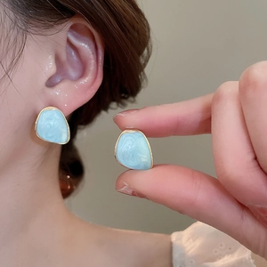 Detail of light blue tulip earring with gold edges and marbled resin texture