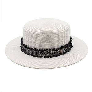 Detailed texture of white boater straw hat with tweed ribbon and gold M logo