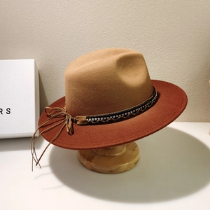 Detail of wool felt fedora with woven band and leather tassel on a wooden stand