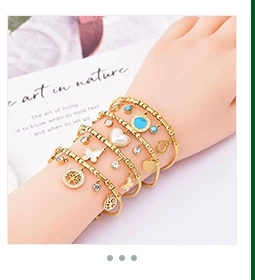 Detail of layered gold bohemian bracelet set with white butterfly and heart charms
