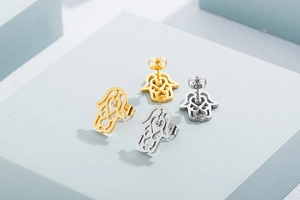 Detail of gold and silver Hamsa Hand stud earrings with sparkling central crystals