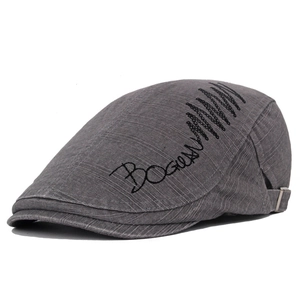 Close-up of grey newsboy cap with black letter embroidery and adjustable metal buckle