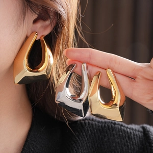 Detailed comparison of gold and silver irregular U-shaped earrings on model ear and hand