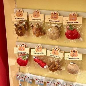Detailed view of assorted plush food charms including croissant and strawberry on retail display