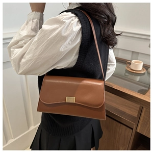Detail view of a brown leather shoulder bag with a gold rectangular striped metal buckle