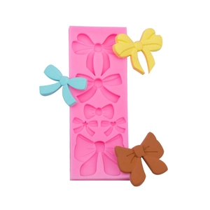 Pink silicone bow mold with finished colorful candy bow shapes for cake decorating