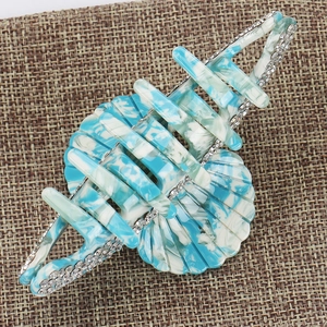 Detail of blue acetate hair claw clip with marble pattern and sparkling rhinestones