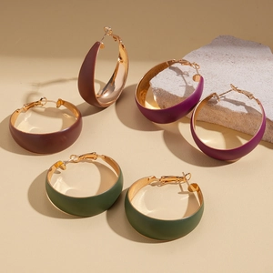 Three large matte geometric hoop earrings in brown, purple, and green with gold interior