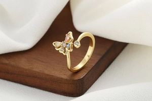 Close-up of golden butterfly ring with colorful cubic zirconia on a wooden display