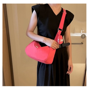 Detail of neon pink nylon crossbody bag with adjustable strap and mini round pouch pendant