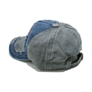 Detail of distressed denim baseball cap with vintage embroidery and frayed edges