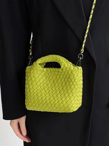 Detailed view of yellow woven mini bucket bag with metallic chain strap on model