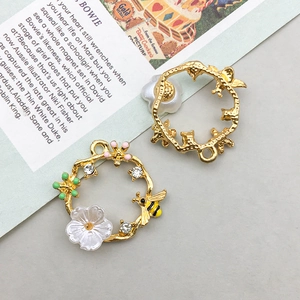Detail of DIY jewelry charms showing a golden bee pendant with shell flowers and rhinestones