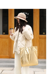 Golden metallic tote bag styled with a beige quilted jacket in a casual street setting