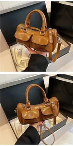 Close-up of brown glossy saddle bag with dual front pockets and silver hardware
