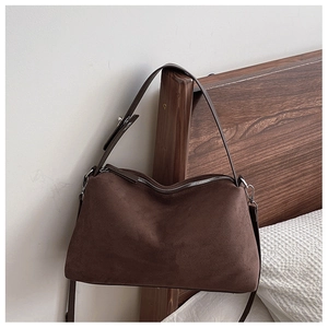 Detail of dark brown suede shoulder bag with silver zipper and soft leather texture