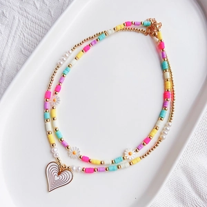 Detail of layered bohemian necklace with daisy beads and a white heart pendant