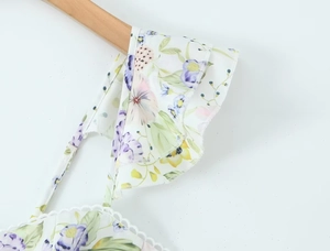 Détails de la robe blanche à fleurs avec volants violets et fines bretelles