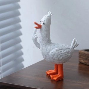 Creativa statuetta di anatra buffa nordica con dito medio su un tavolo di legno
