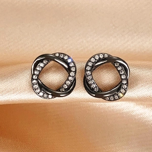 Sparkling cubic zirconia entwined earrings in dark metal on elegant champagne silk fabric