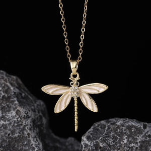 Detailed view of dragonfly pendant with white enamel wings and sparkling zircon pavé