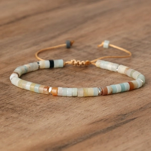 Detail view of woven beaded emperor stone bracelet with adjustable cord on wood