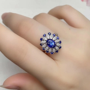 Exquisite flower ring with blue sapphire gemstone and sparkling zircon stones on finger