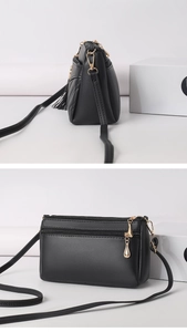 Detailed view of black PU leather crossbody bag, showing multi-layer zipper and fine strap.