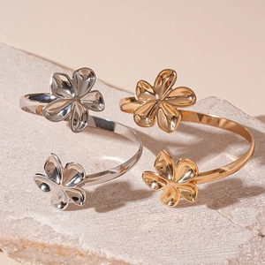 Polished silver and gold metallic irregular open flower arm cuffs on a stone surface