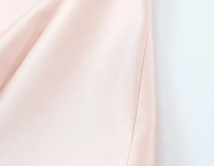 Détail de tissu satiné rose lisse avec des plis souples et une texture brillante élégante