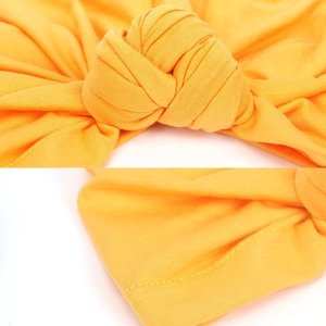 Detail of yellow knit turban showing intricate knot craftsmanship and fine stitching quality