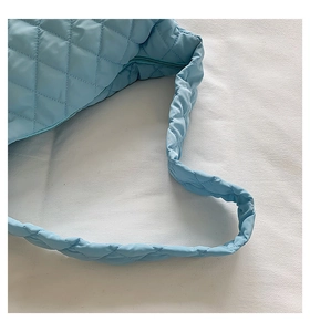 Close-up of sky blue quilted shoulder strap detail on a large lightweight puffy cloud bag