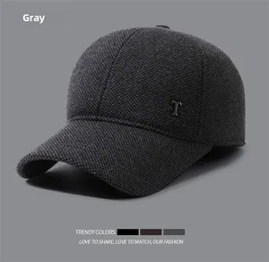 Detail of grey winter baseball cap with textured knit fabric and metal T decoration