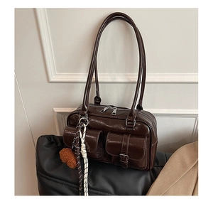Close-up of dark brown vintage faux leather shoulder bag with pockets and plush pendant