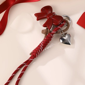 Detail view of red bow keychain with heart pendant and red-white braided rope
