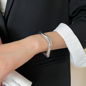 Polished silver wave cuff bracelet shown on model's wrist with professional business attire