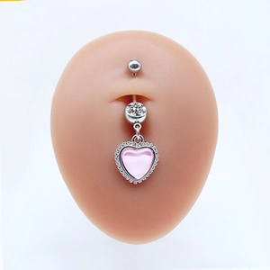Macro view of silver belly ring with a pink heart pendant and clear crystals on skin