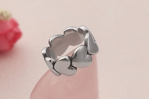 Detailed view of silver heart-shaped interconnected ring on a soft pink display stand