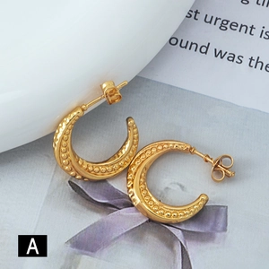 Detailed close-up of gold C-shaped earrings with intricate caviar beaded texture and finish
