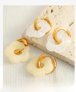 Macro shot of camellia flower earrings in white and beige resin on a stone base