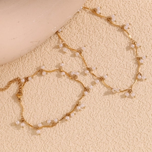 Detailed close-up of 18K gold plated wavy chain necklace with elegant white pearls