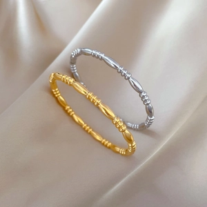 Minimalist gold and silver titanium steel beaded bangles on beige silk background