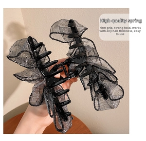 Détail d'une grande pince à cheveux noire en dentelle avec maille argentée et ressort robuste