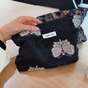 Detailed embroidery of butterflies on a black jacquard fabric makeup storage bag