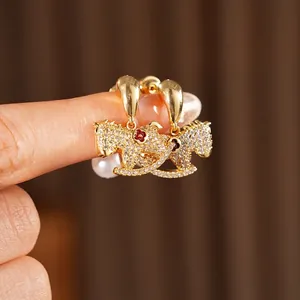 Gold rocking horse earrings with sparkling crystals, a red flower, and drop pearls