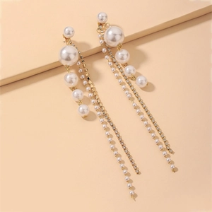 Detail view of asymmetric long tassel earrings with pearls and rhinestones on beige base