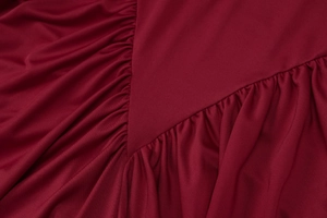 Close-up of deep red sleeveless dress featuring refined pleated texture and draping